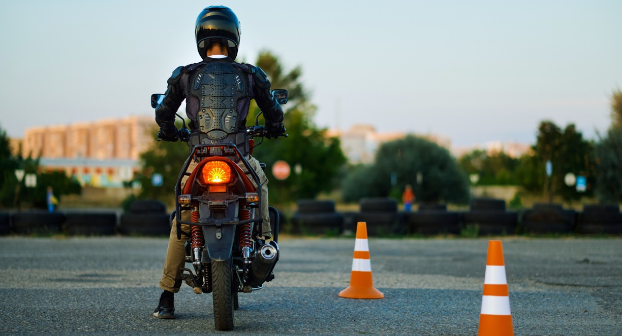 Motard en tenue de protection sur une piste d'entrainement avec plots