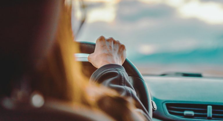 Main sur le volant d'une conductrice pendant un trajet en fin de journee