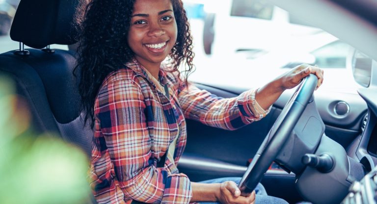 Jeune conductrice souriante au volant de sa voiture