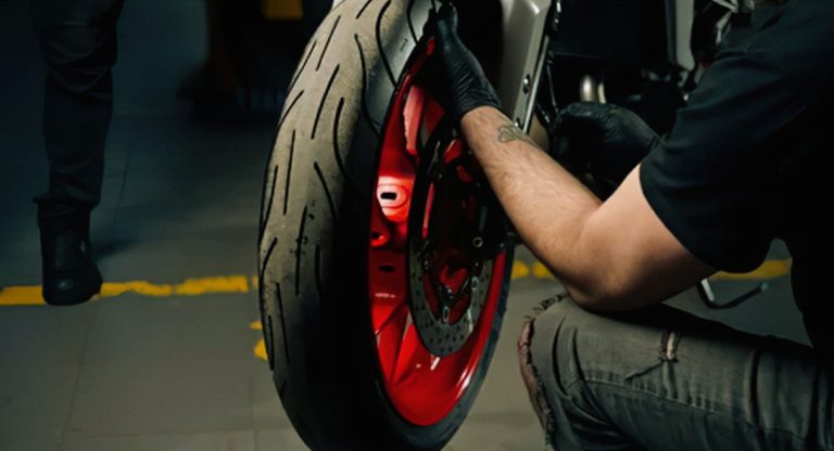Mécanicien inspectant la roue avant d'une moto en garage