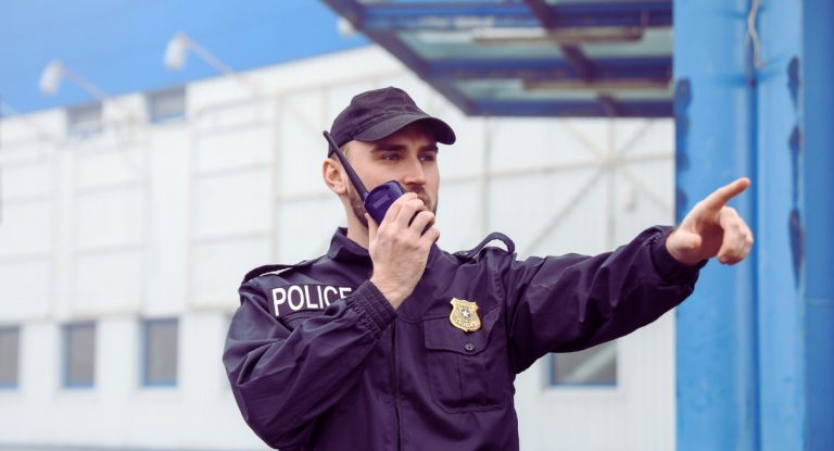 Policier en uniforme parlant à la radio en patrouille dans une rue